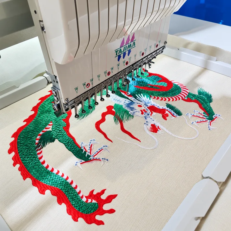 Embroidery machine stitching a dragon design on light fabric