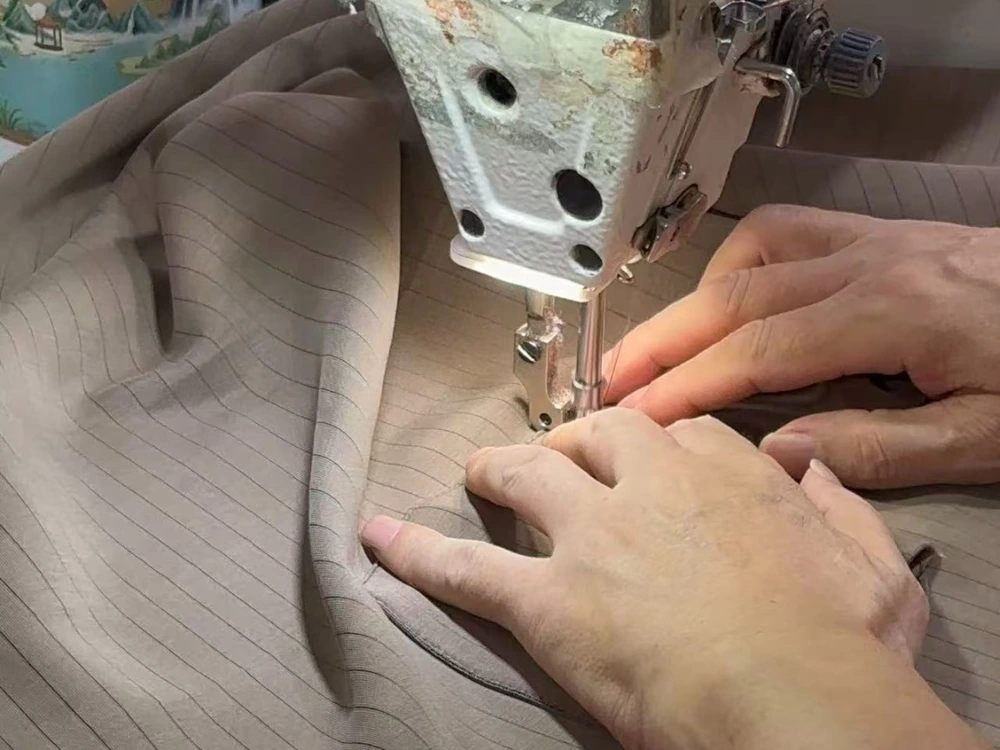 Worker guiding striped fabric through an industrial sewing machine