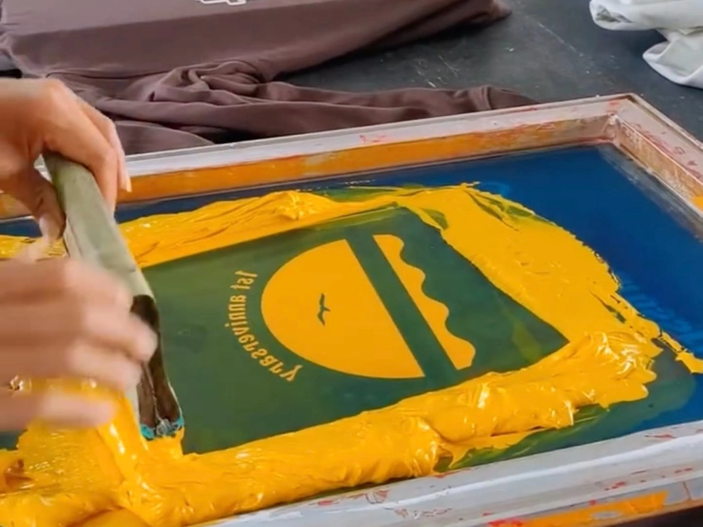 ink being applied through a screen-printing stencil onto a garment