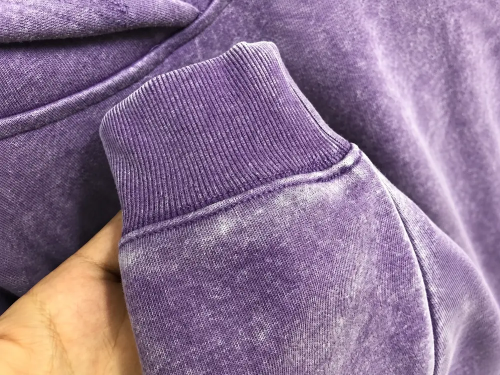 Purple washed hoodie cuff showing ribbing, seam stitching and faded fabric texture