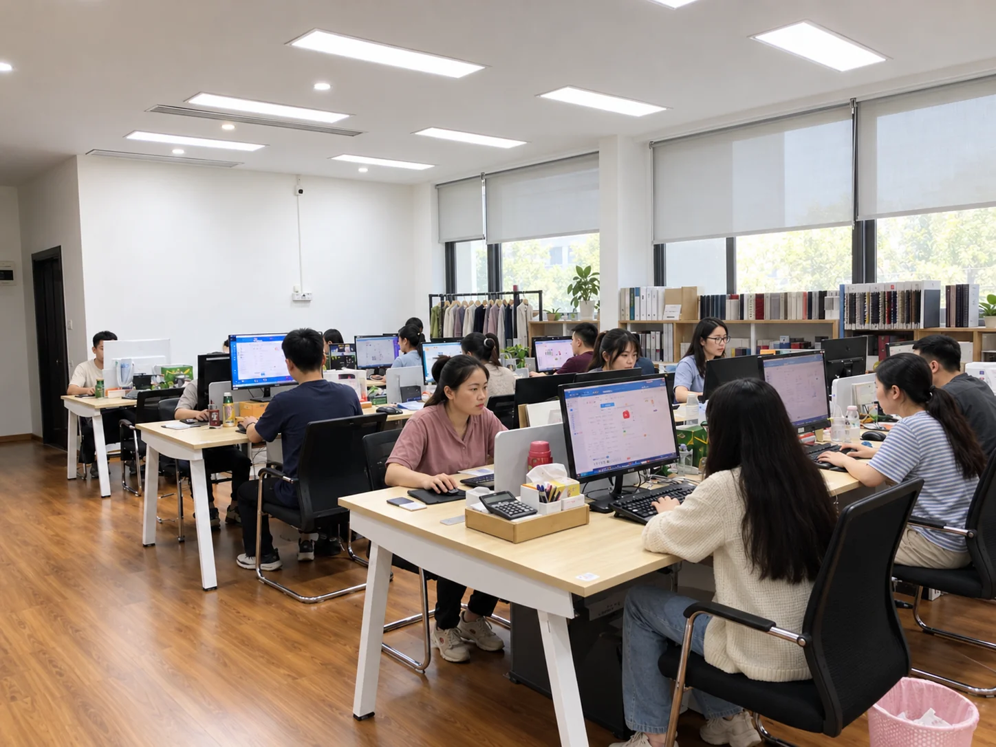 Staff working at computers in an apparel office with fabric swatches and garment samples
